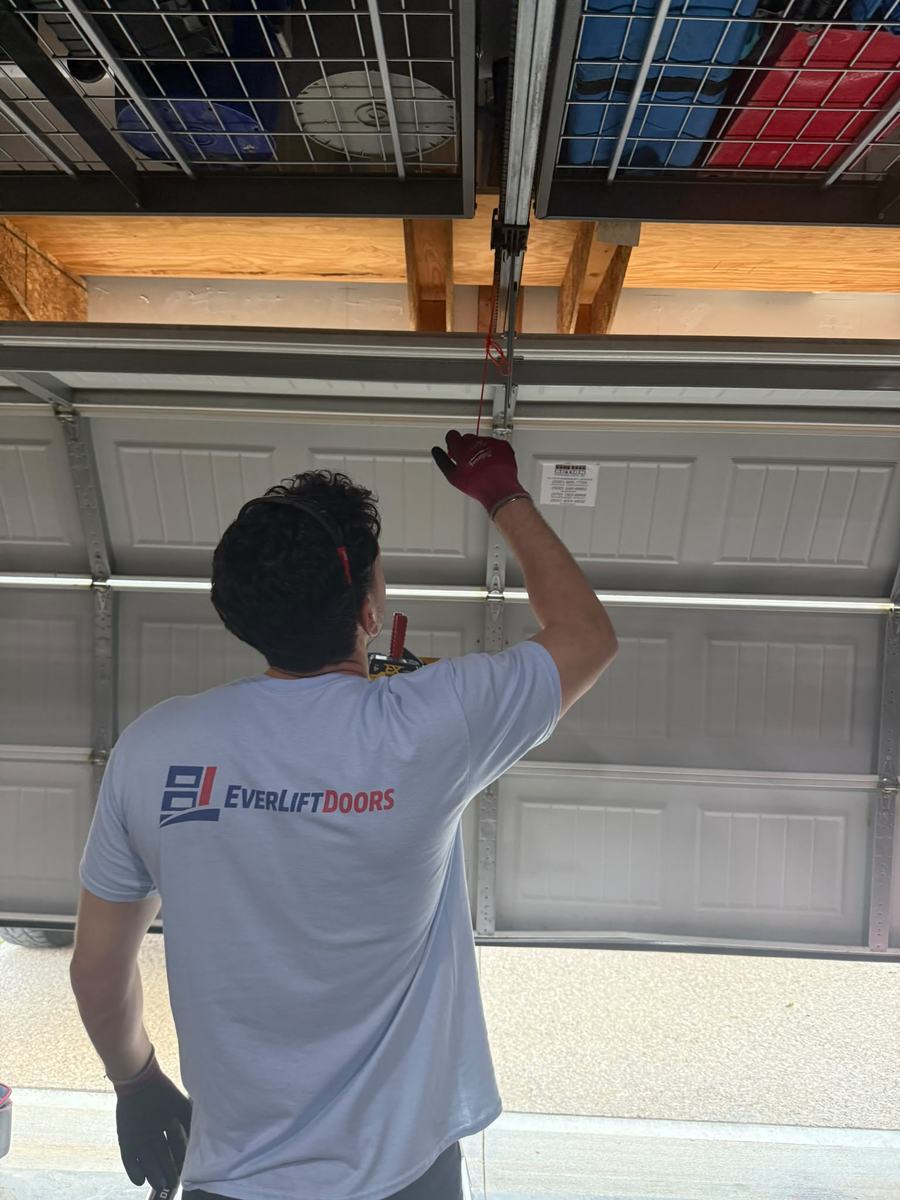 EverLift Doors technician in company shirt servicing a garage door opener rail on a real job in Kentucky