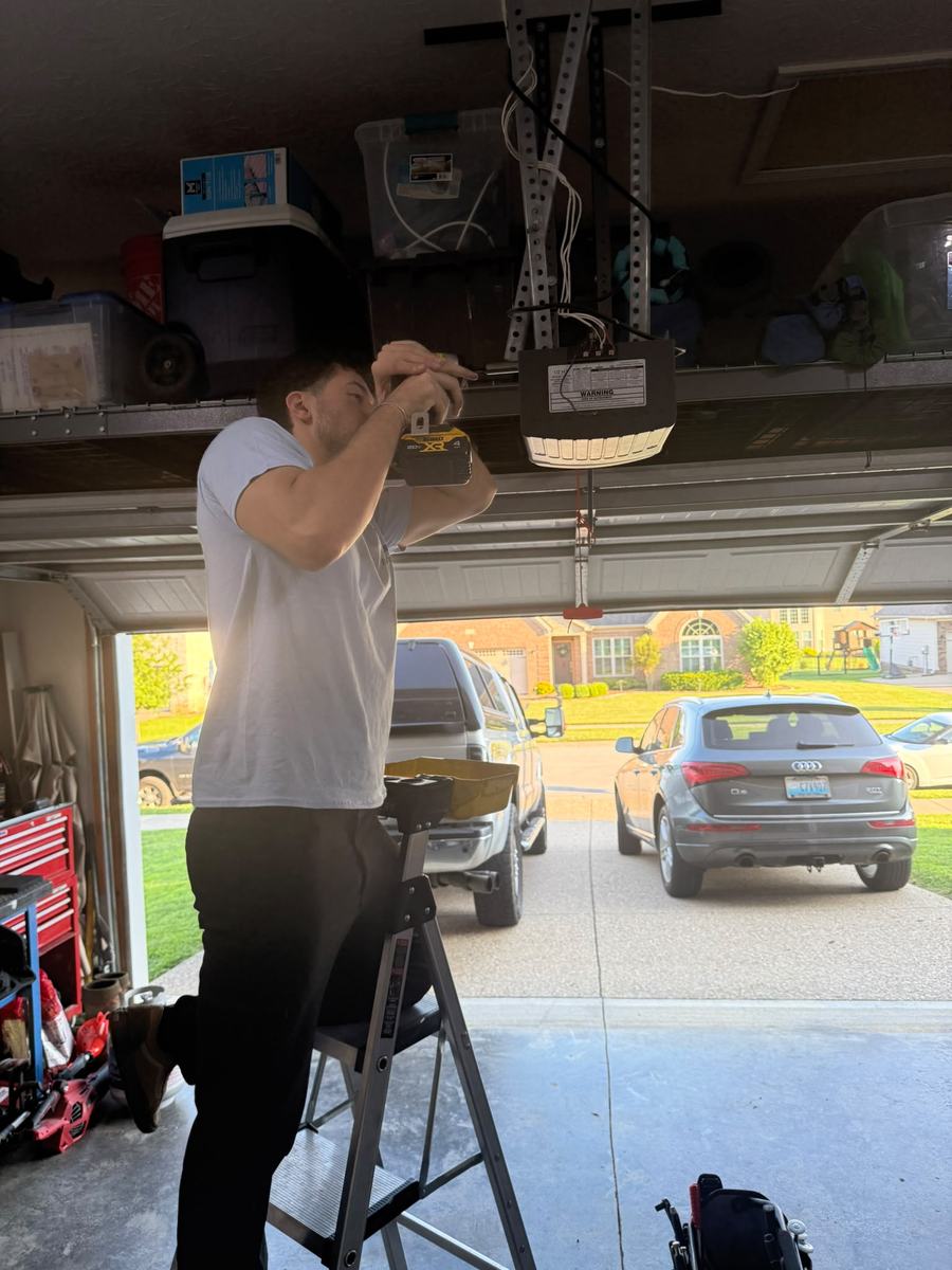 EverLift Doors technician on a ladder wiring a garage door opener in a Kentucky suburban garage