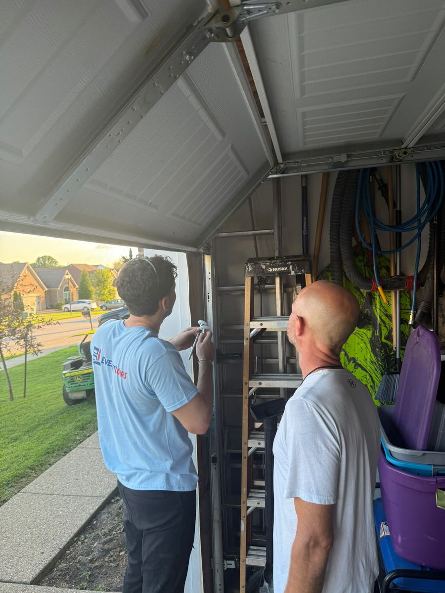 EverLift Doors technician repairing a garage door track for a homeowner at sunset in a Kentucky neighborhood